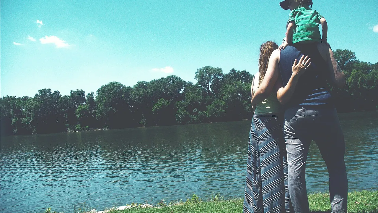 Family standing by lake — warm lifestyle scene